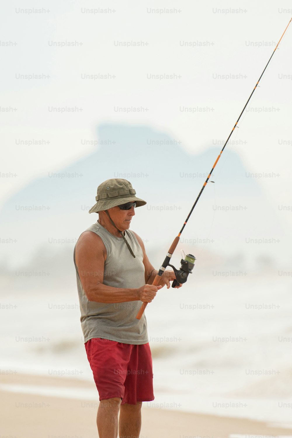 um homem em pé em uma praia enquanto segura uma vara de pesca