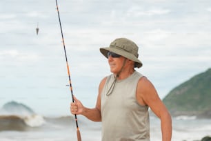 a man standing on a beach holding a fishing pole