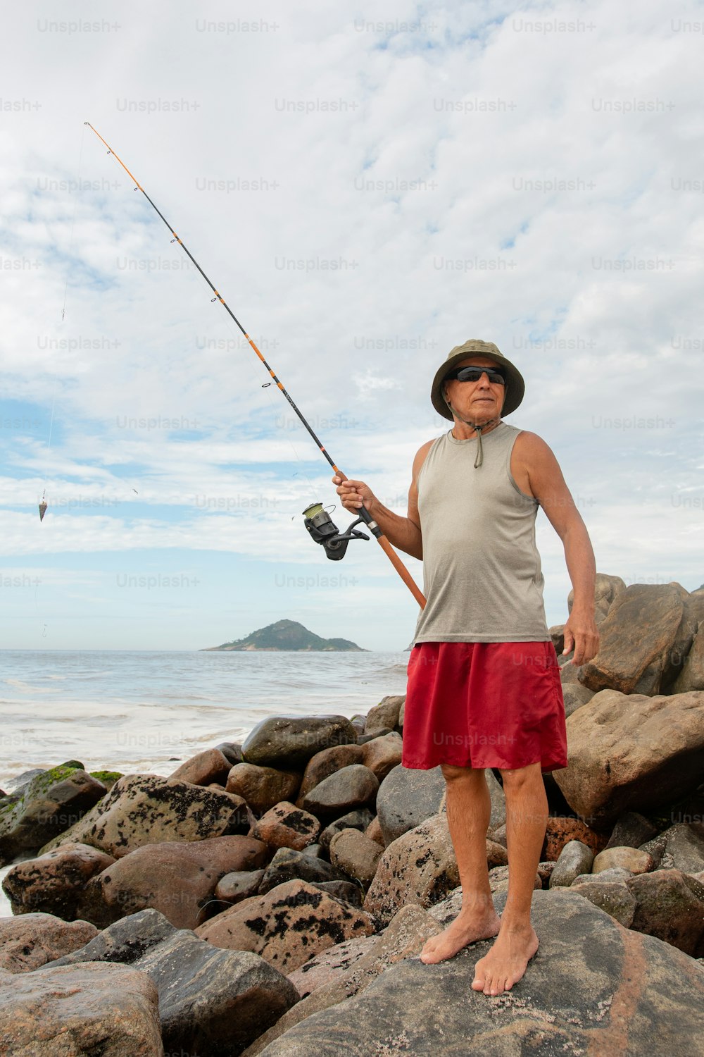 um homem de pé em uma rocha com uma vara de pesca