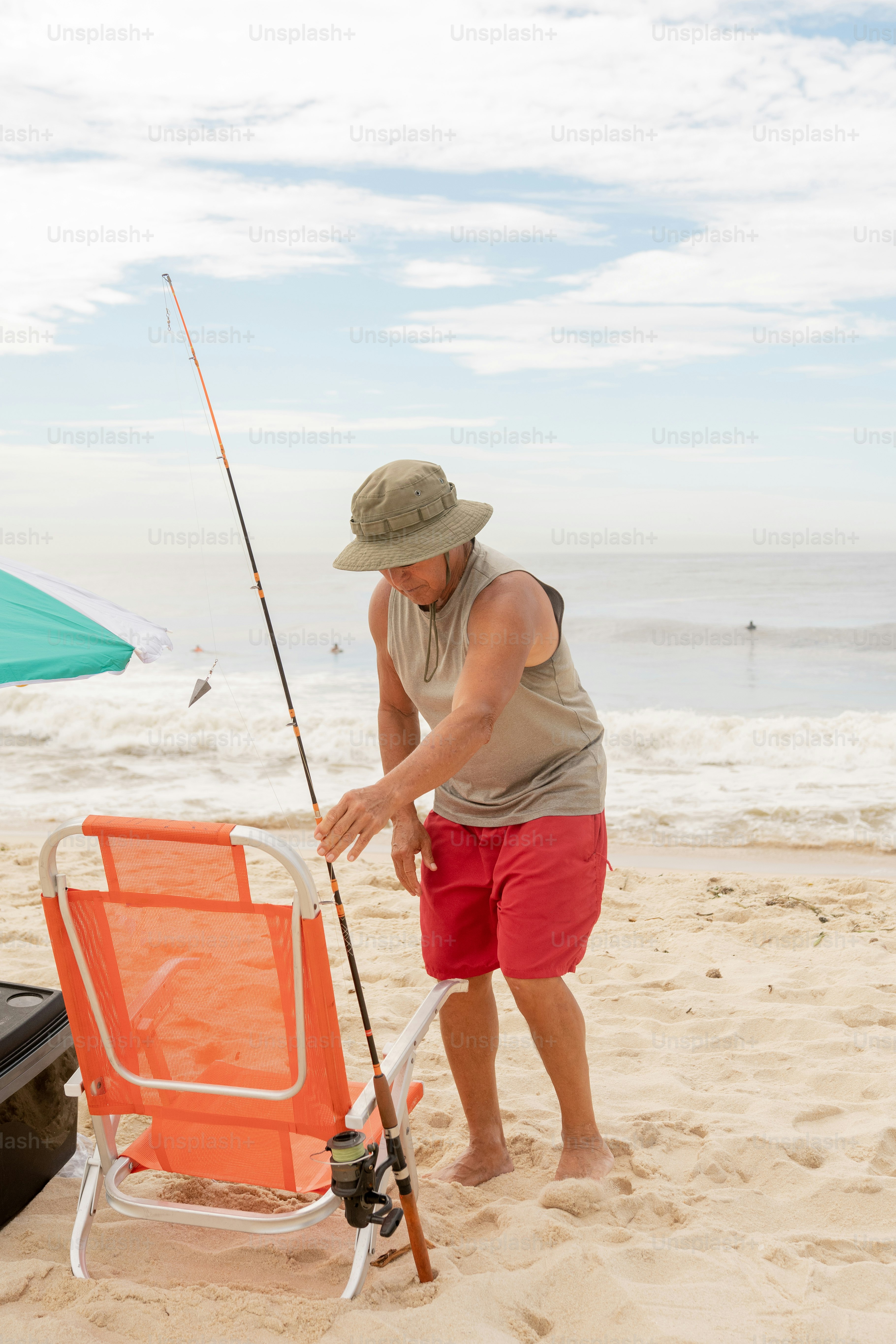 um homem de pé em uma praia segurando uma vara de pesca