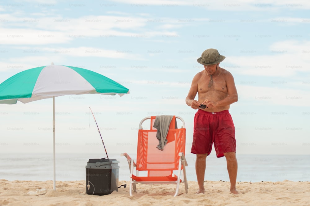 a man standing on a beach next to a chair and umbrella