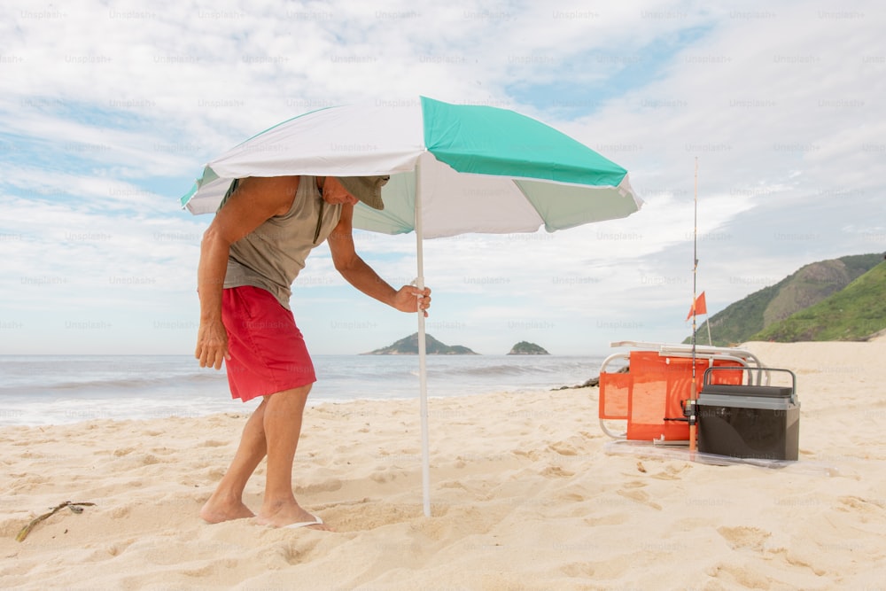 Ein Mann steht am Strand und hält einen Regenschirm in der Hand
