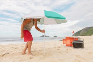 a man standing on a beach holding an umbrella