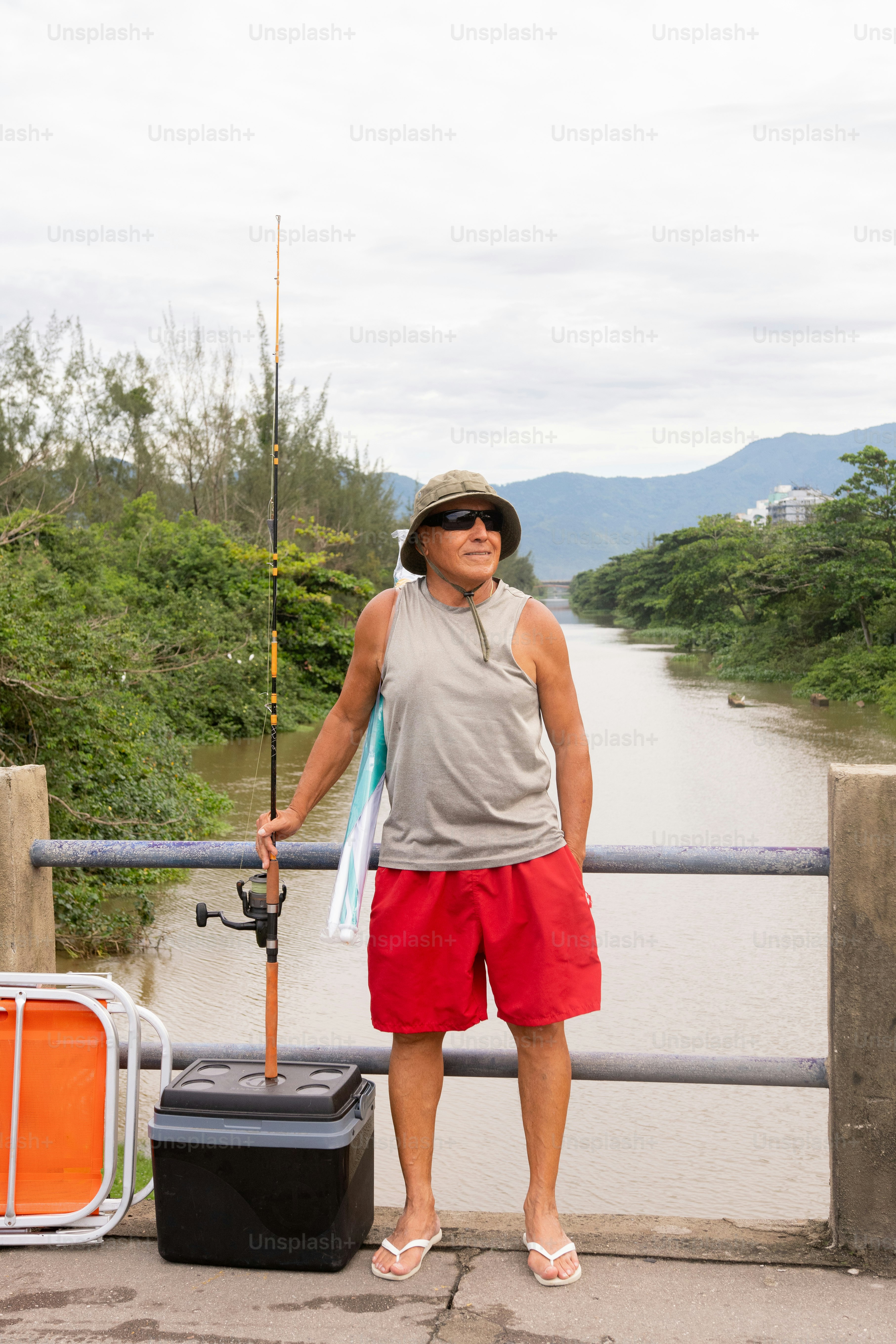 um homem de pé ao lado de um rio segurando uma vara de pesca