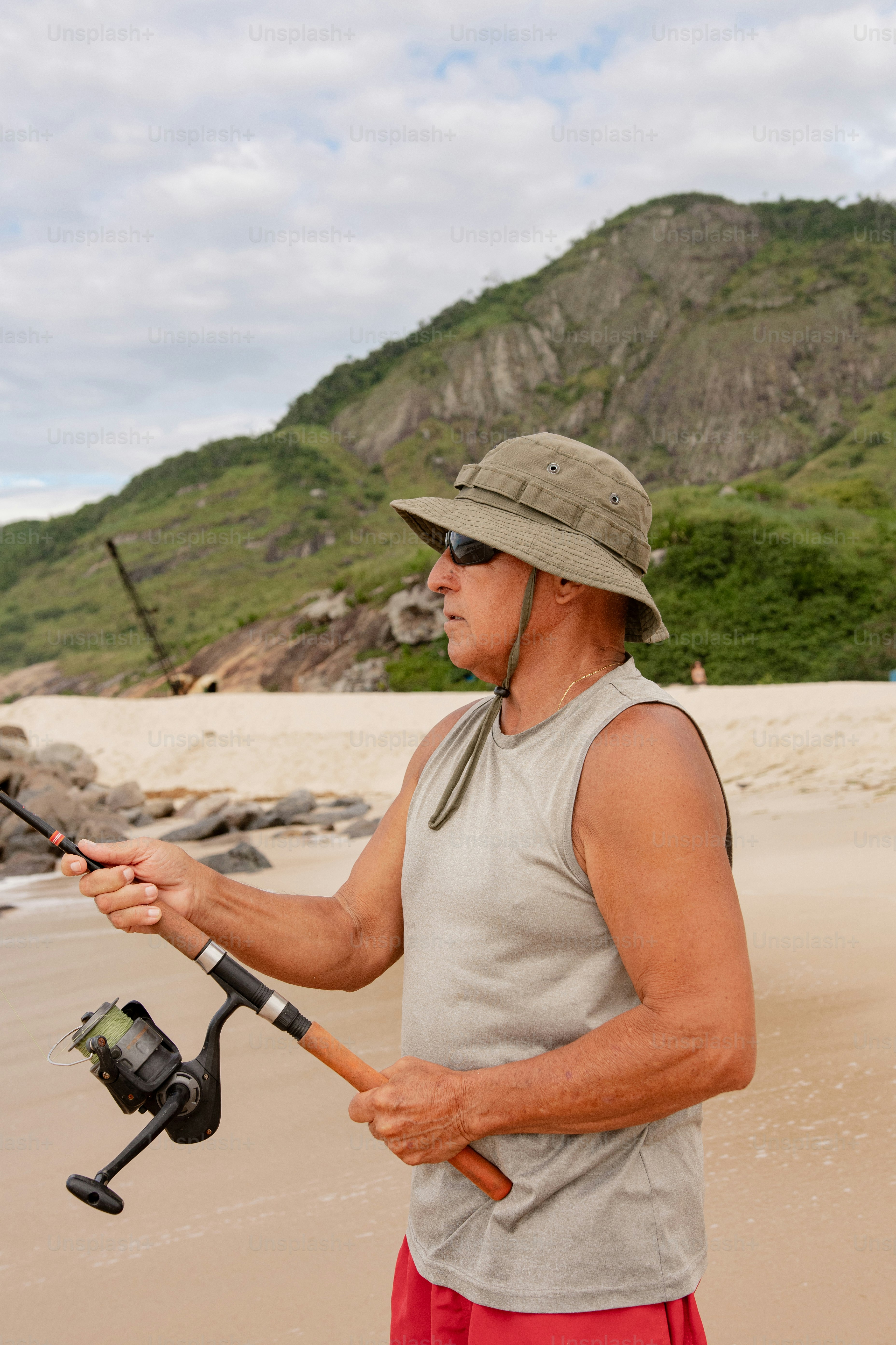 um homem em pé em uma praia segurando uma vara de pesca