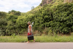 a man walking down a road carrying a suitcase