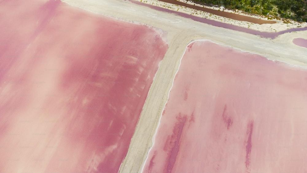 an aerial view of a pink field with trees in the background