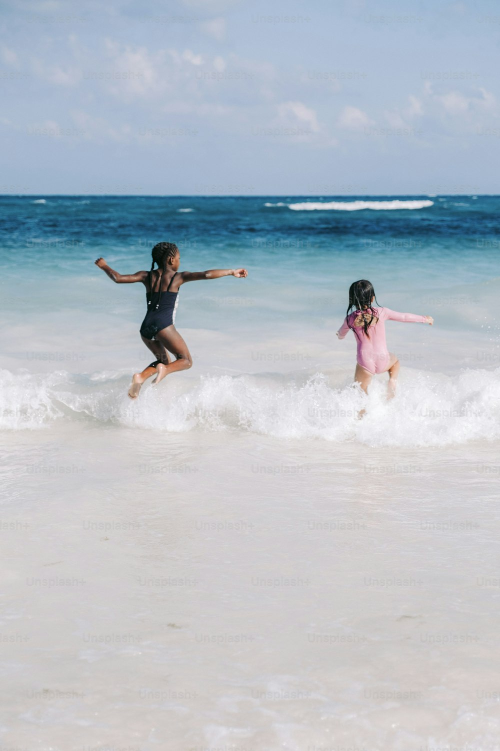 two young girls playing in the ocean on a sunny day