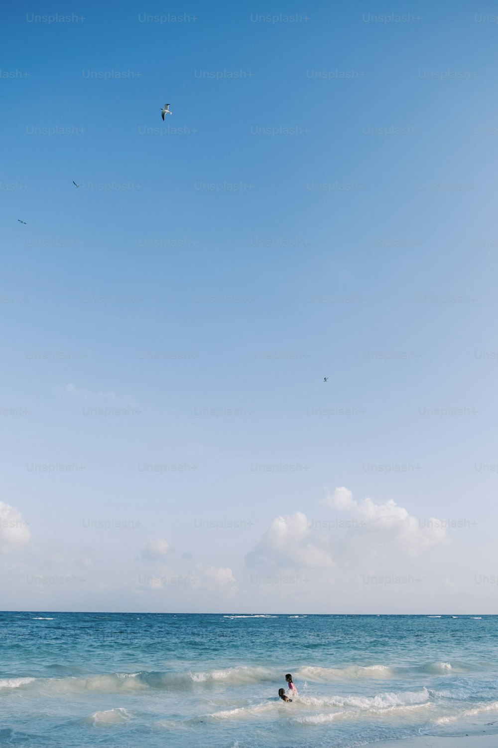 a person swimming in the ocean with a kite in the sky
