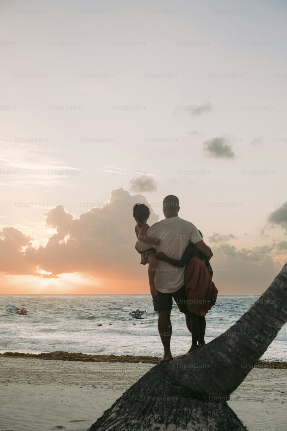 a man and a woman standing on a palm tree at the beach