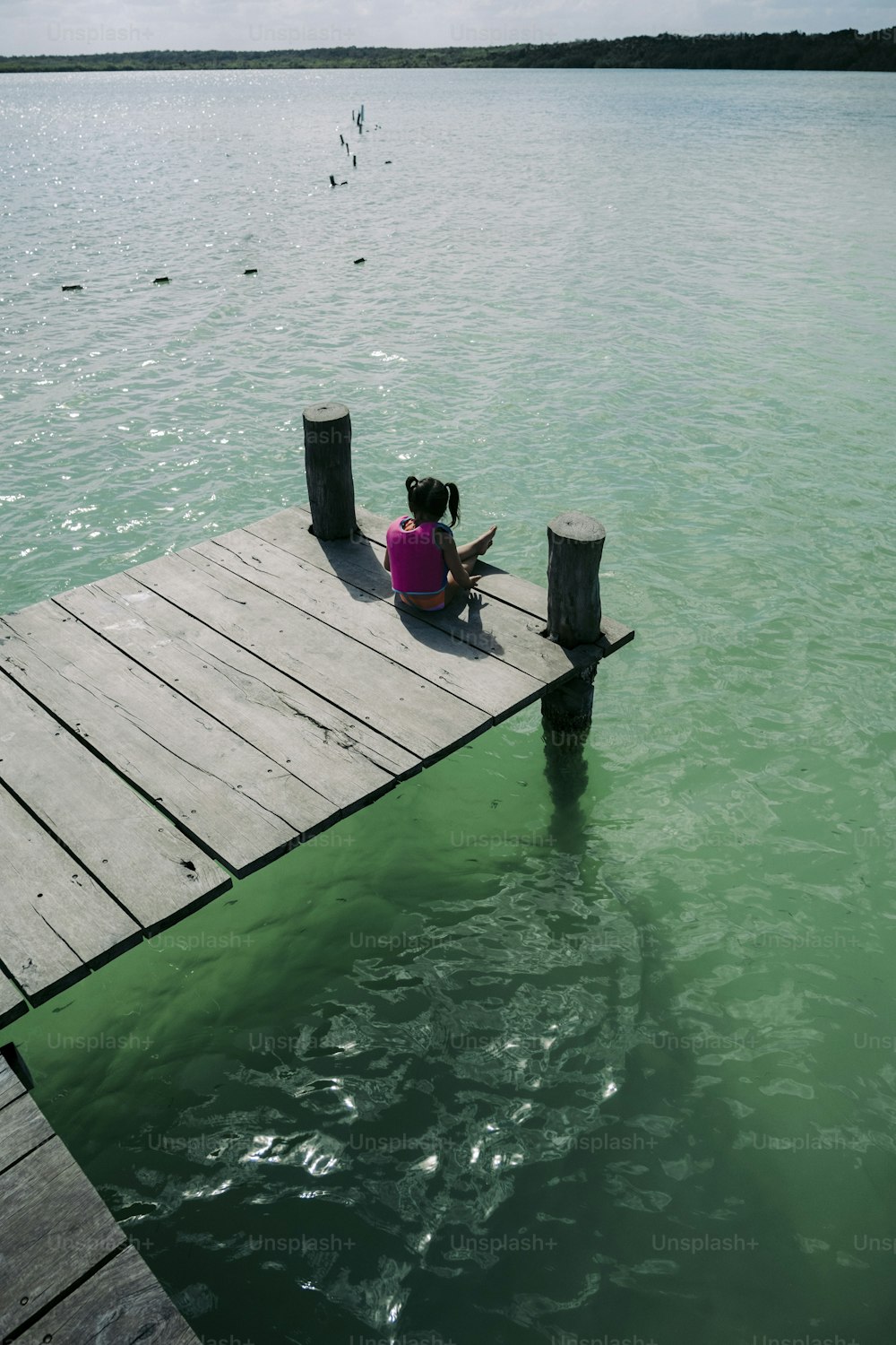eine Person, die auf einem Dock im Wasser sitzt