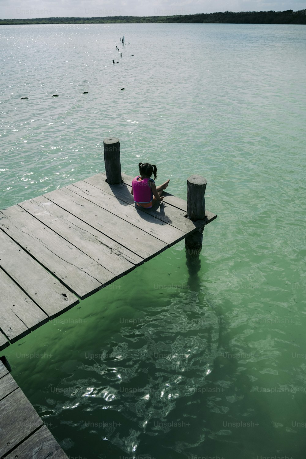 a person sitting on a dock in the water