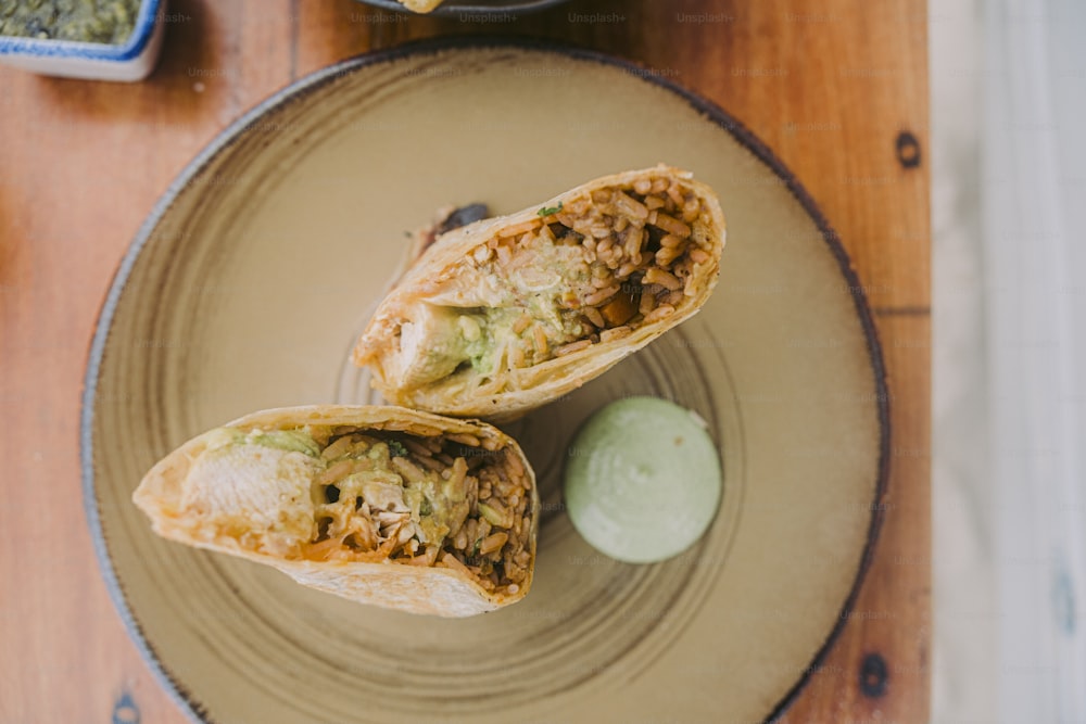 two burritos on a plate with a pickle on the side