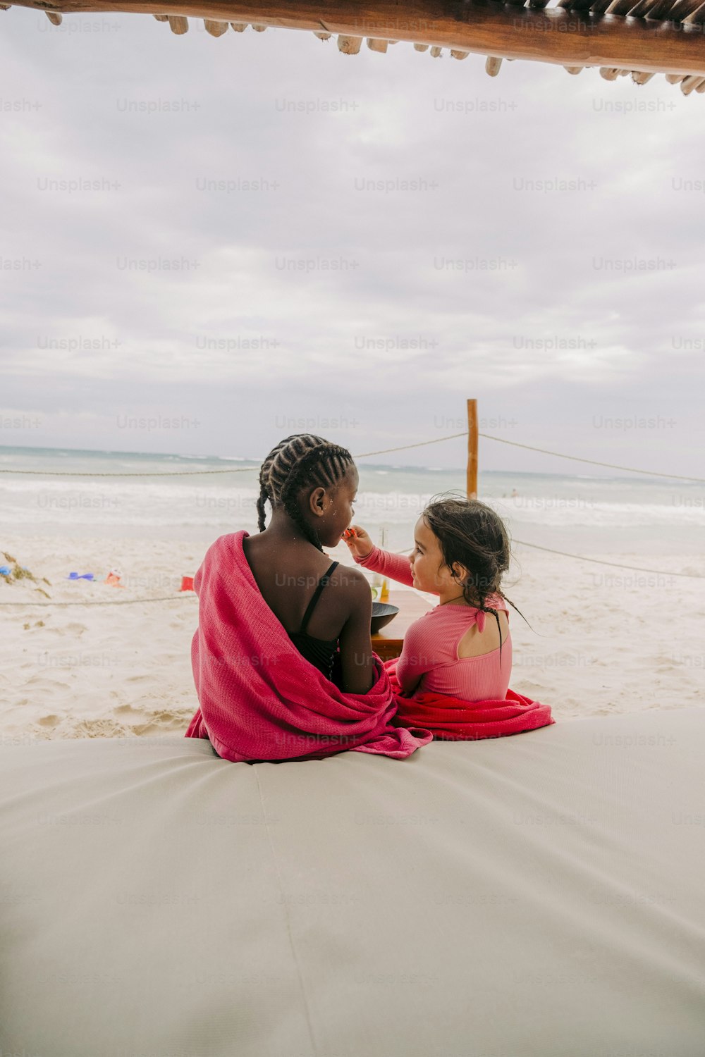 Una coppia di donne sedute sulla cima di una spiaggia sabbiosa