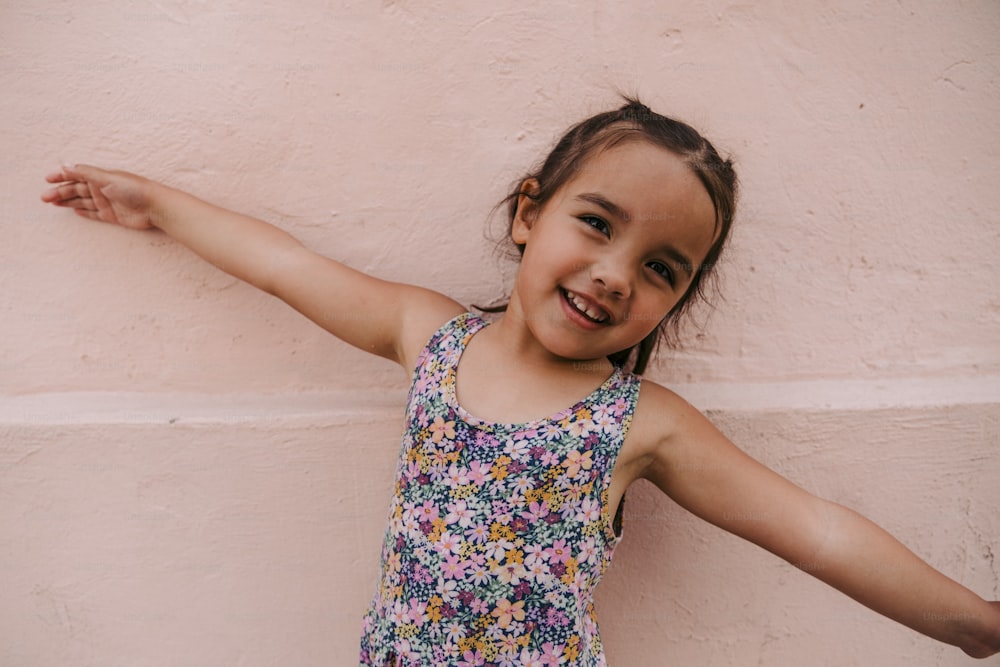 a little girl standing in front of a pink wall