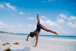 a woman doing a handstand on the beach