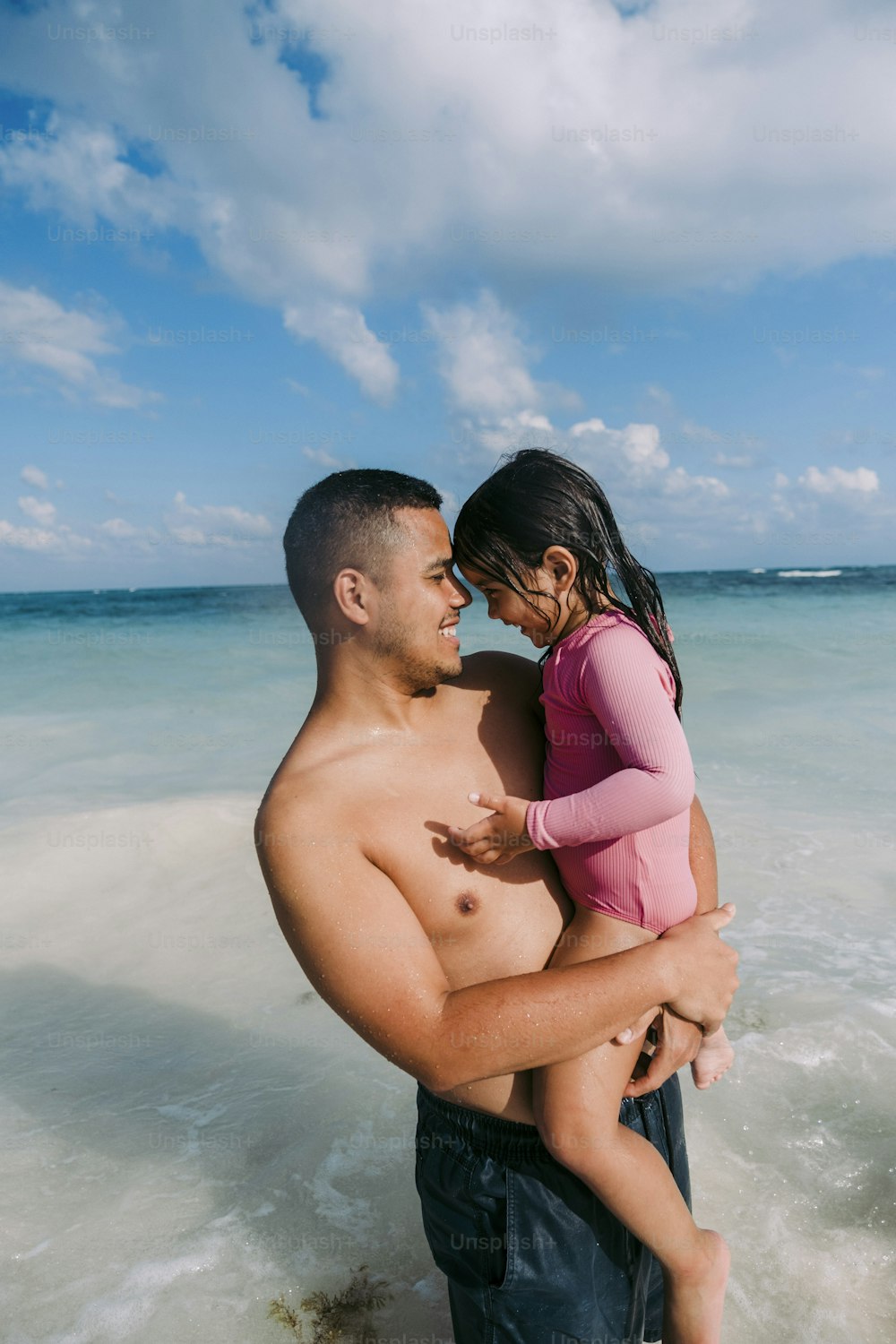 Un hombre sosteniendo a una niña en la playa