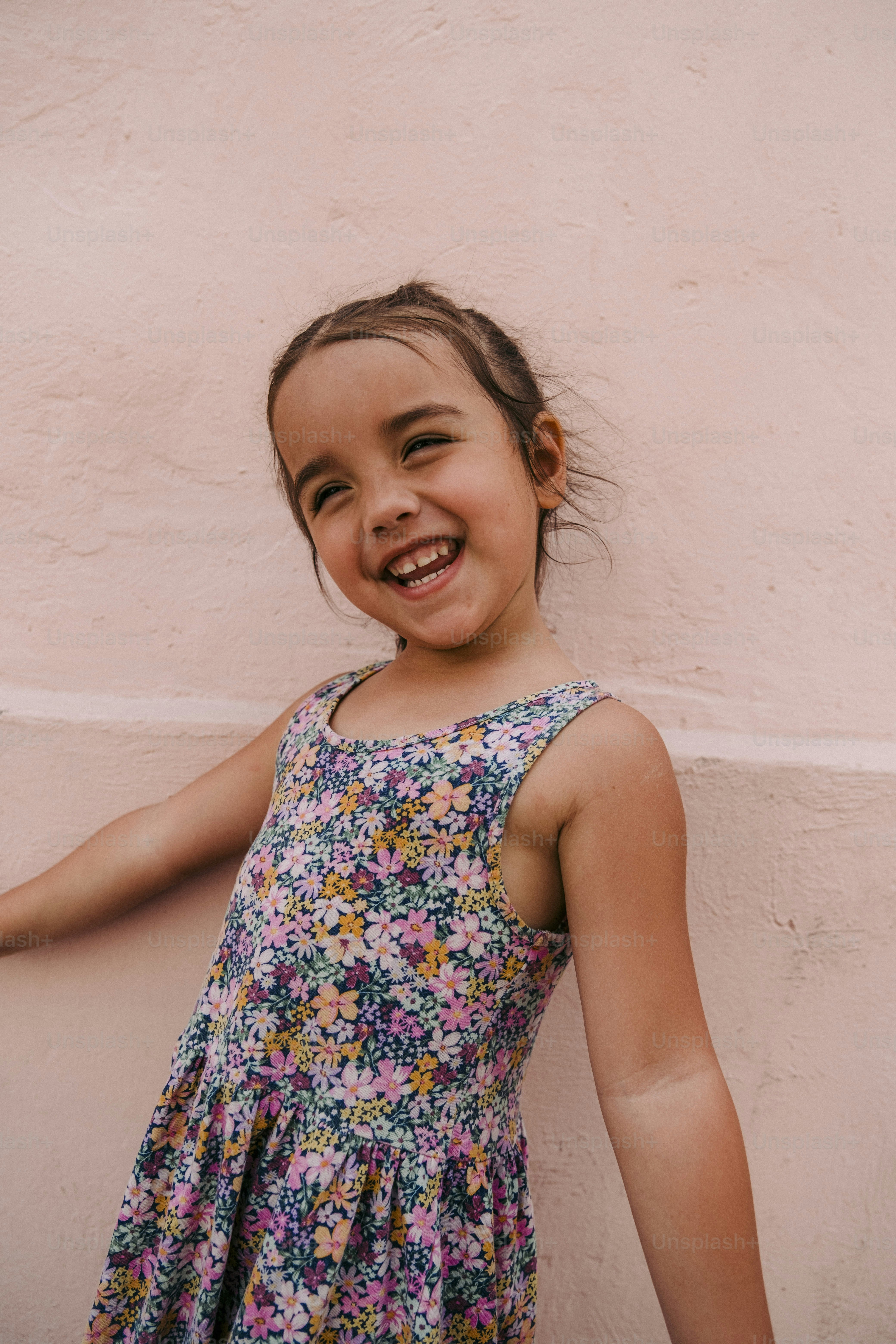 a little girl standing in front of a pink wall