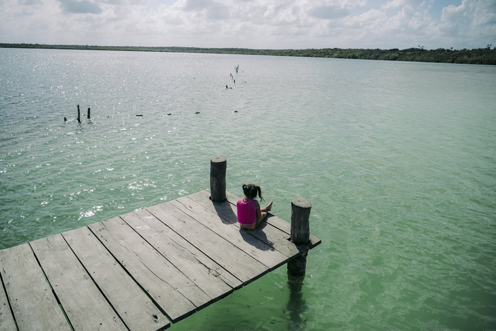 a person sitting on a dock in the water