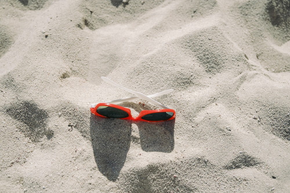 砂の中に横たわる赤いサングラス