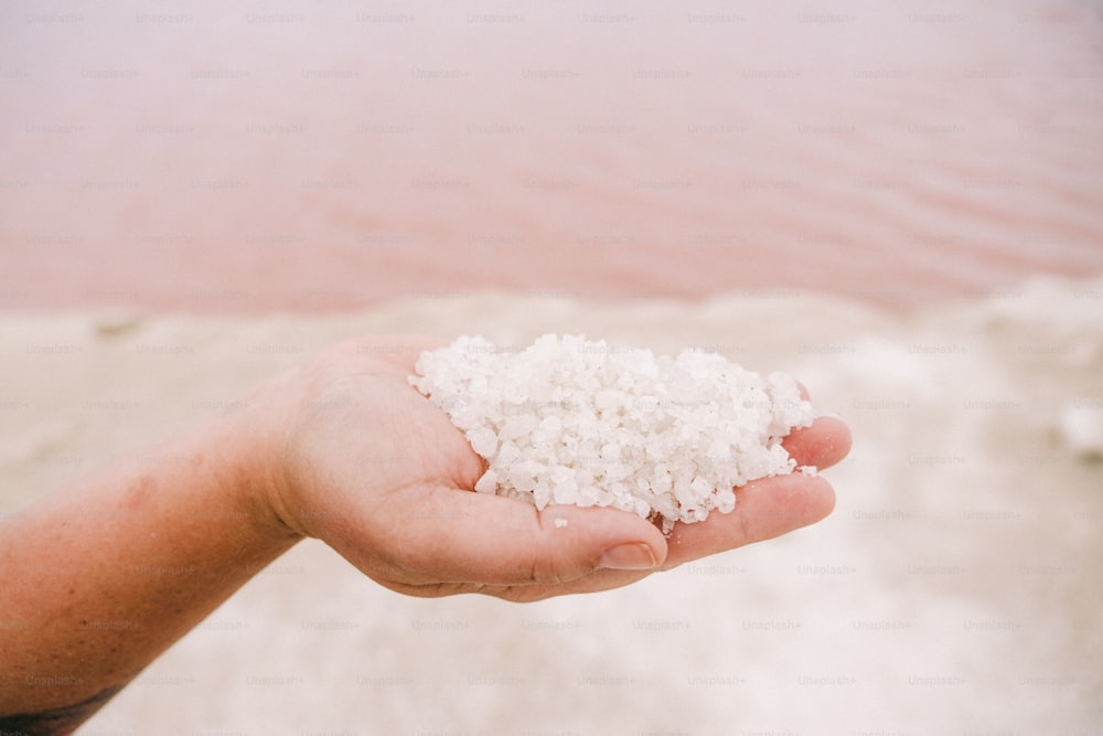 a person holding a handful of sea salt in their hand