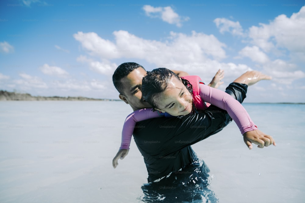 Un hombre cargando a una niña en el agua