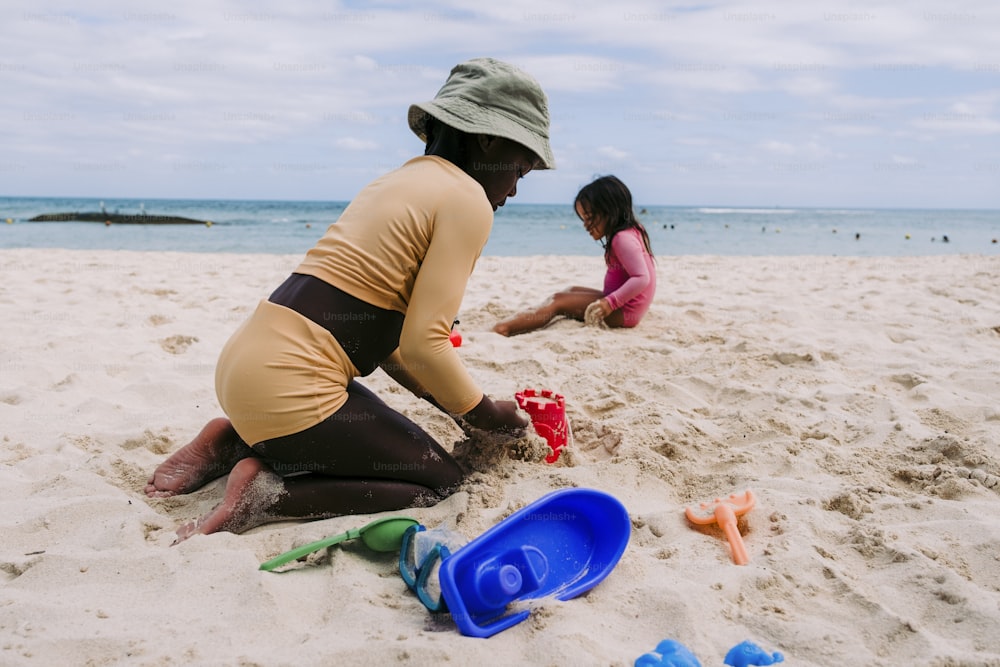 a woman and a child playing in the sand at the beach