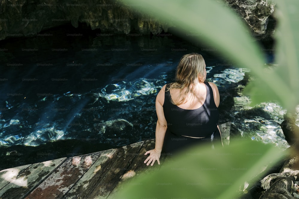 a woman in a black tank top standing on a ledge