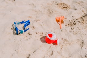 a red and blue toy fire hydrant sitting on top of a sandy beach