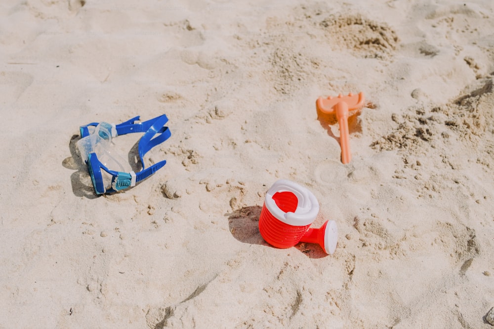 a red and blue toy fire hydrant sitting on top of a sandy beach