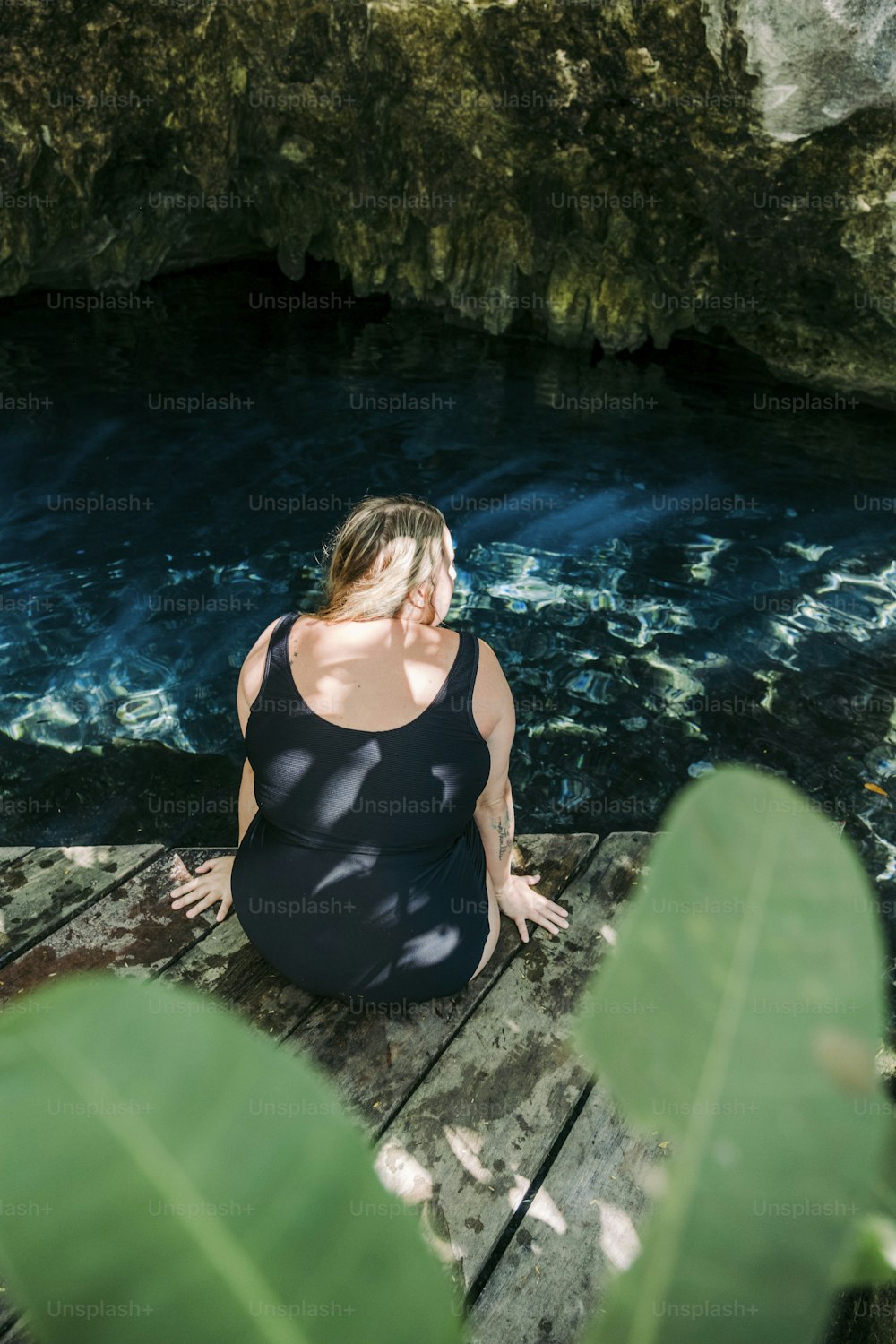 uma mulher sentada em uma doca olhando para a água
