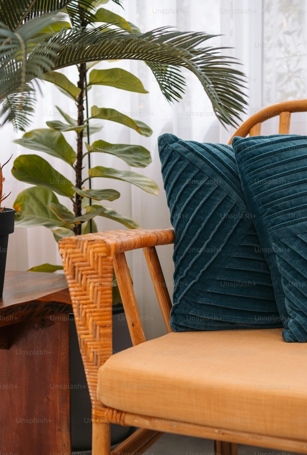 a chair with two pillows on it next to a potted plant