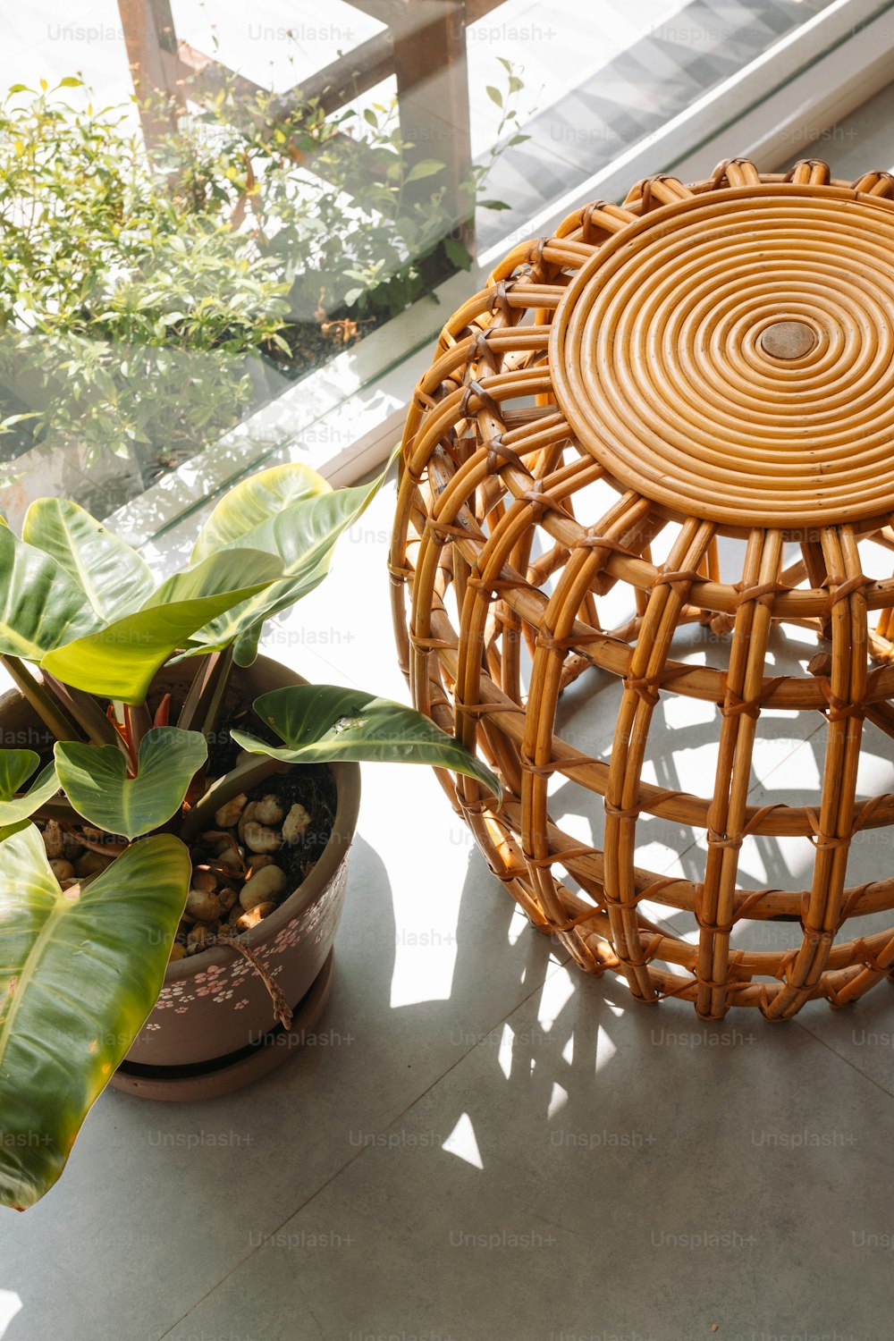 a wicker stool and a potted plant on a window sill