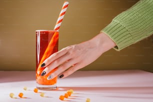 a woman's hand reaching for an orange drink in a tall glass