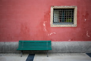 a green bench sitting in front of a red wall