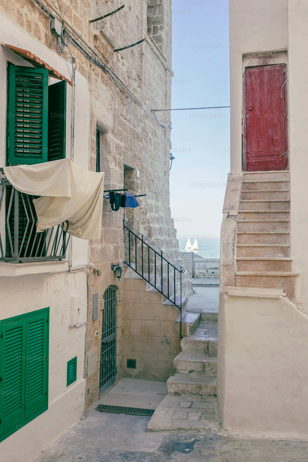 a narrow alleyway with a red door and green shutters