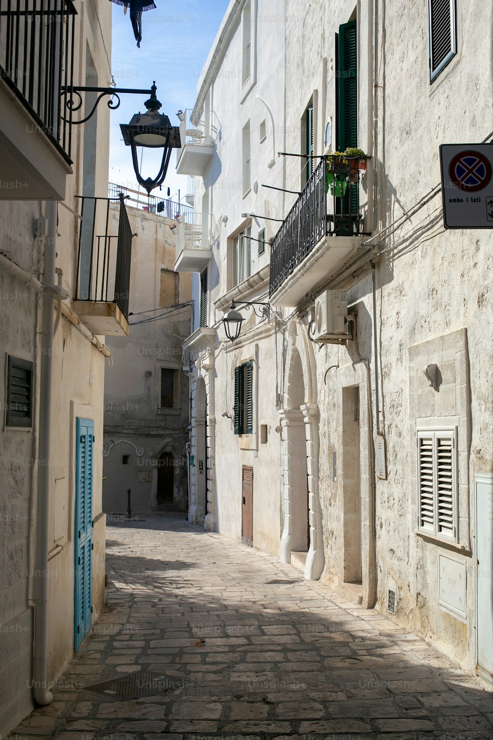 a narrow alley way with white buildings and blue shutters