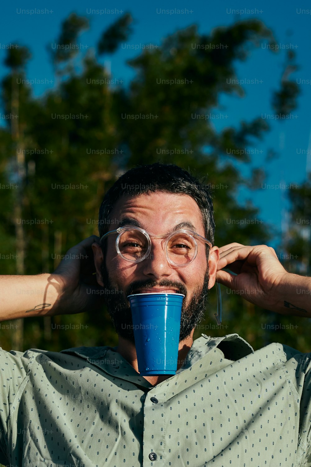 Un hombre con una taza de café cubriéndose la cara