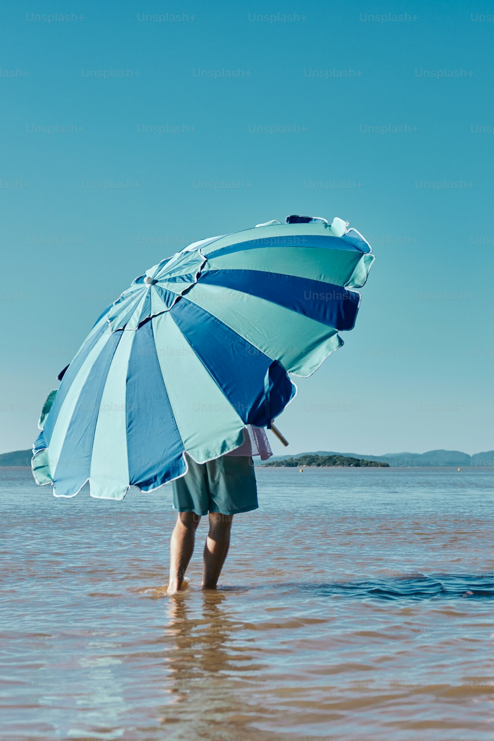 eine Person, die mit einem Regenschirm im Wasser steht