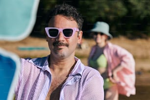 a man wearing sunglasses and a pink shirt
