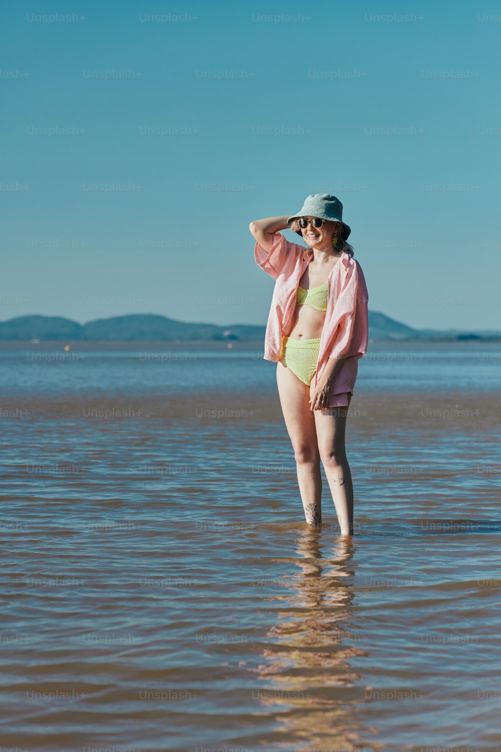 a woman standing in the water wearing a hat