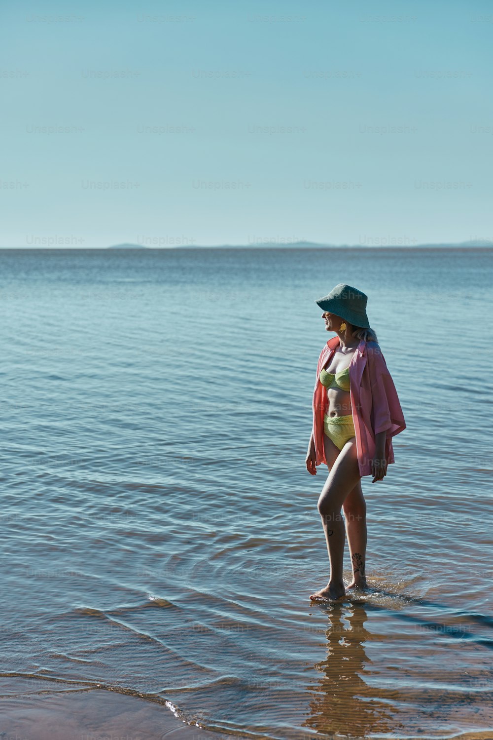 a woman standing in the water wearing a green hat