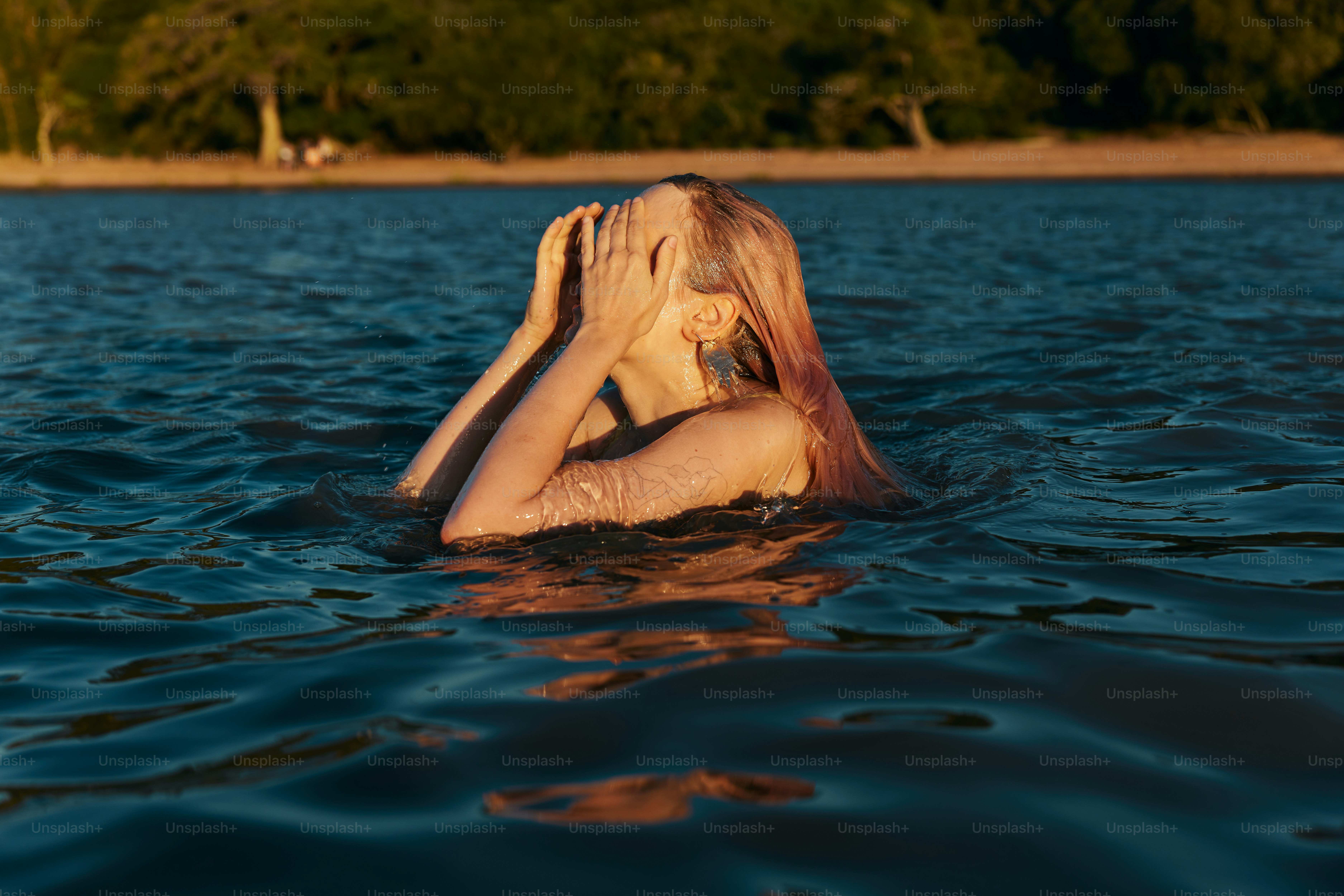 a woman in the water covering her face with her hands