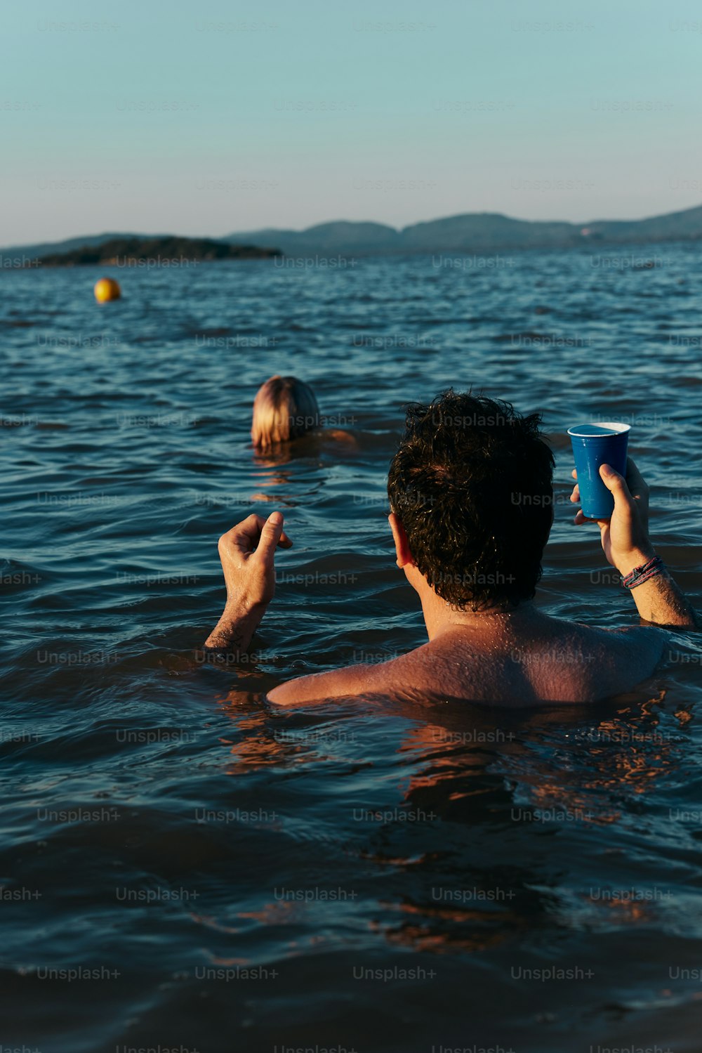 a man floating in the water while holding a cup