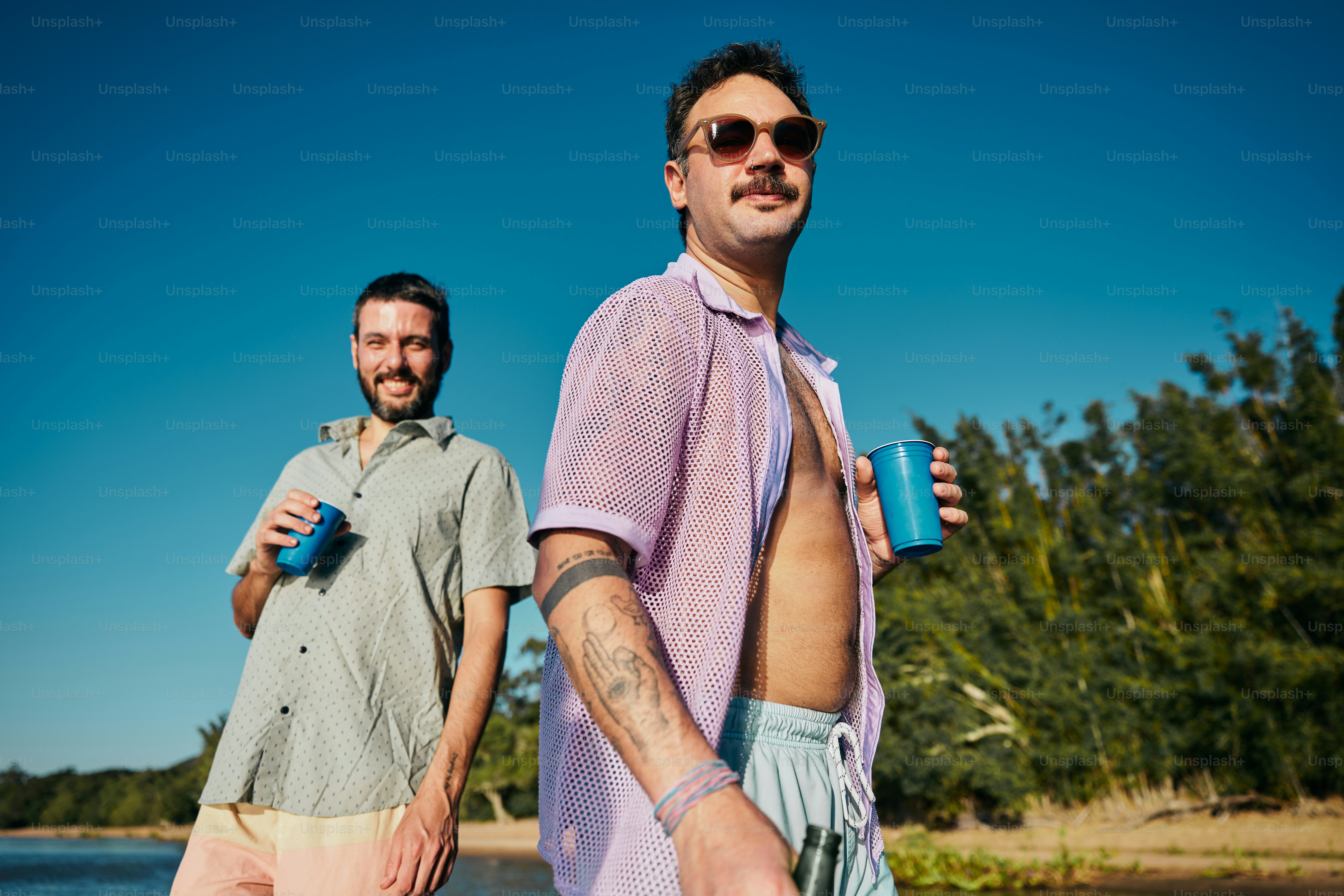 A couple of men standing next to each other photo – Beach Image on Unsplash