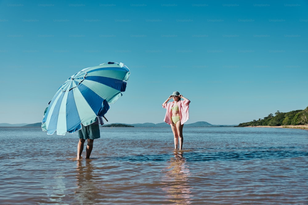 two people standing in the water with an umbrella