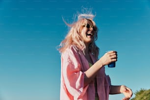 Una mujer con una camisa rosa sosteniendo una taza azul