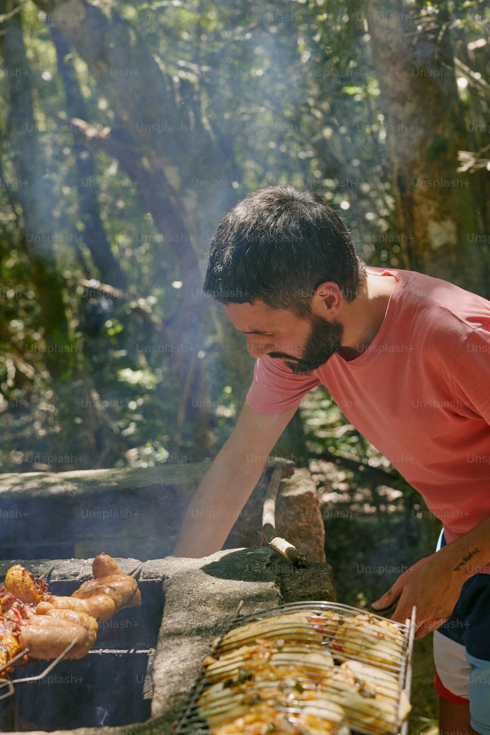 a man cooking food on a grill in the woods
