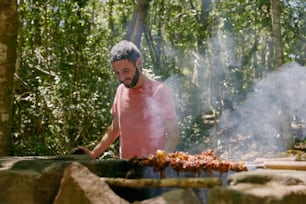 a man cooking on a grill in the woods