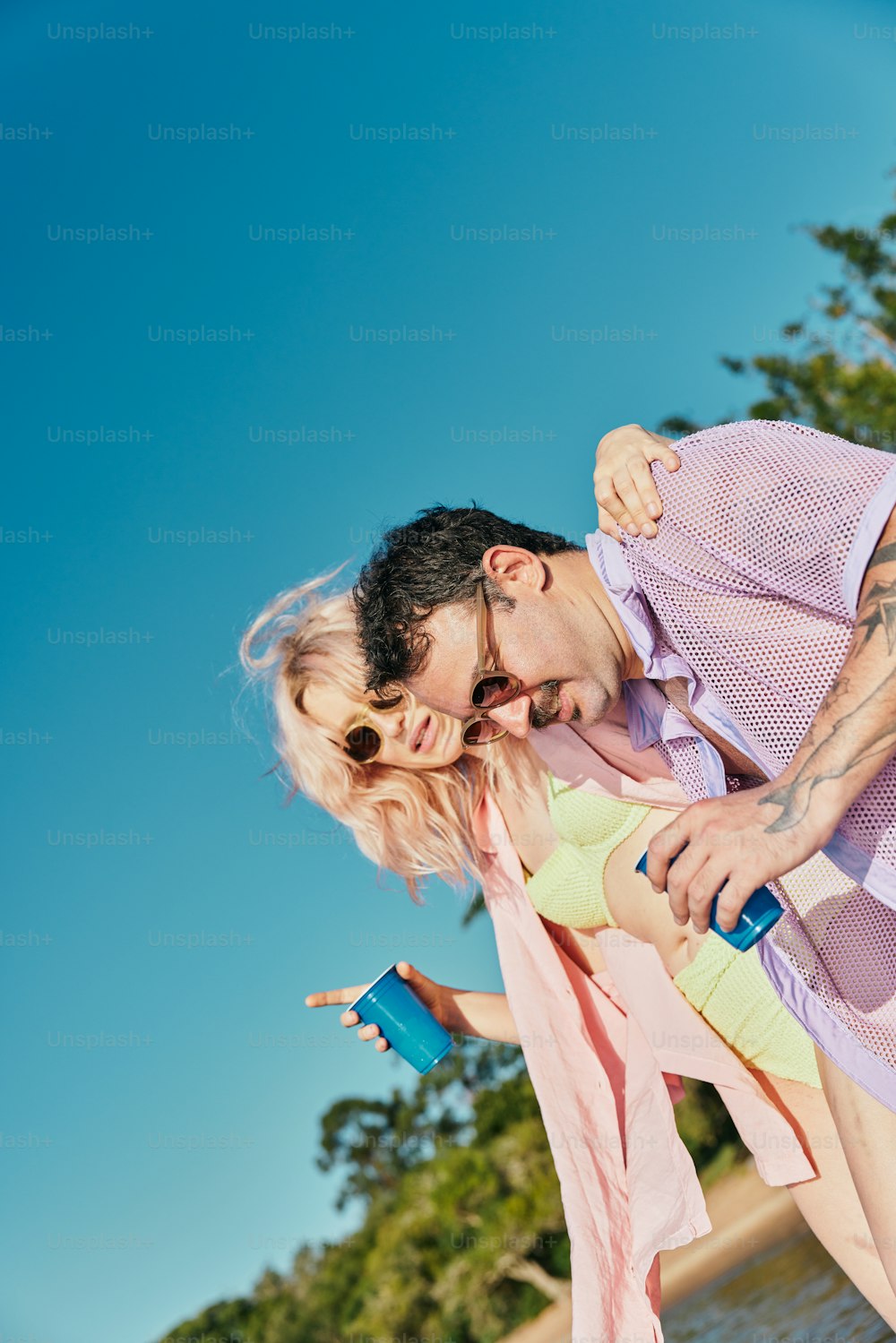 a man and a woman on a beach with trees in the background